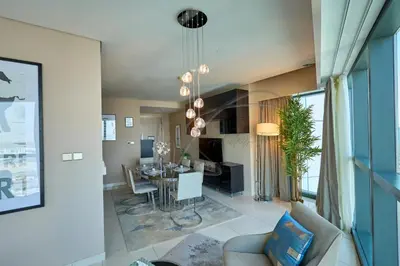 a dining room and living room with a table and chairs at DAMAC Paramount Towers 2BHK by WS Holiday Homes in Dubai