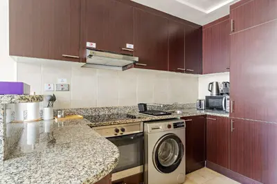 a kitchen with wooden cabinets and a washing machine at Silkhaus Gallery Studio at Sky Gardens in DIFC in Dubai