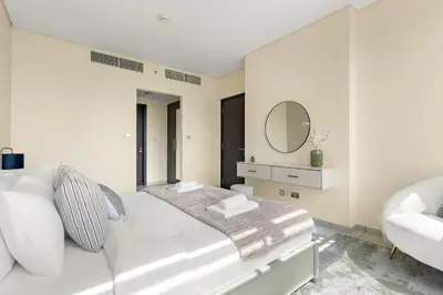 a white bedroom with a white couch and a mirror at Silkhaus Premium 1BDR Stay with DIFC Views in Dubai