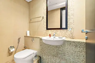 a bathroom with a sink and a toilet and a mirror at Silkhaus Premium 1BDR Stay with DIFC Views in Dubai