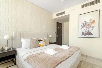 a white bedroom with a large bed and a table at Silkhaus Classic 1BDR in DIFC at Sky Gardens in Dubai
