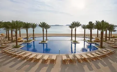 an infinity pool with chairs and palm trees on the beach at TRPS - Fairmont North Residences, Palm Jumeirah - Luxurious 2BR plus Maids, Sea and Harbour View in Dubai