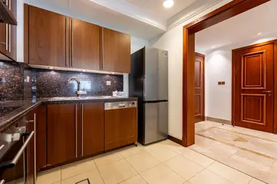 a kitchen with wooden cabinets and a stainless steel refrigerator at TRPS - Fairmont North Residences, Palm Jumeirah - Luxurious 2BR plus Maids, Sea and Harbour View in Dubai