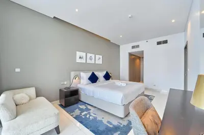 a bedroom with a bed and two chairs and a table at FAM Living - 1 Bedroom Canal View in DAMAC Maison Prive in Dubai