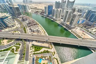a bridge over a river in a city with tall buildings at FAM Living - 1 Bedroom Canal View in DAMAC Maison Prive in Dubai