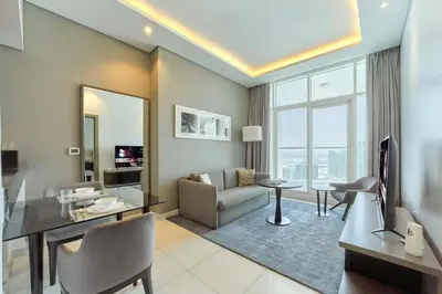 a living room with a couch and a dining room at FAM Living - 1 Bedroom Canal View in DAMAC Maison Prive in Dubai