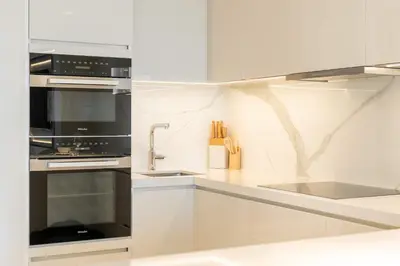 a kitchen with white cabinets and black appliances at PVH - Burj Khalifa View Studio - Emaar Residences in Dubai