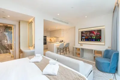 a bedroom with a white bed and a living room at PVH - Burj Khalifa View Studio - Emaar Residences in Dubai