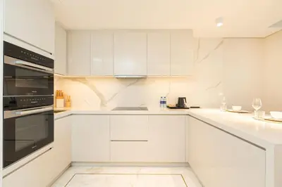 a white kitchen with white cabinets and appliances at PVH - Burj Khalifa View Studio - Emaar Residences in Dubai