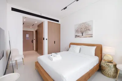 a bedroom with a white bed and a table and chairs at StayShort - Perfect Studio in Binghatti Azure JVC - Sleeps 2 in Dubai