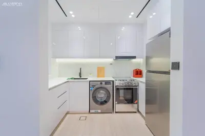 a white kitchen with a washing machine in it at Modern Brand New 1BR Luxury Apartment With Cozy Interiors In Jumeirah Village Circle in Dubai