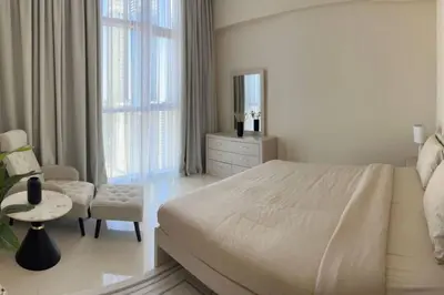 a white bedroom with a bed and a chair at 1BR Amazing Dubai And Sea View in Dubai