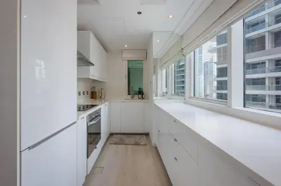 a kitchen with white cabinets and a large window at Modern Luxury Marina Stay with Ain Dubai View - Near JBR Beach in Dubai