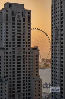 a view of tall buildings with a ferris wheel in the background at Waterfront 1BR Apartment At Heart of Dubai Marina in Dubai