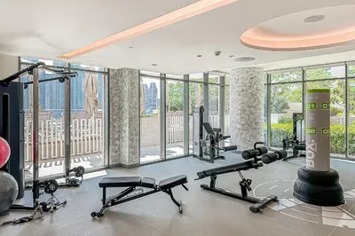 a gym with several treadmills and weights in a room with windows at Modern 2BR Retreat with Stunning Sea Views in Dubai