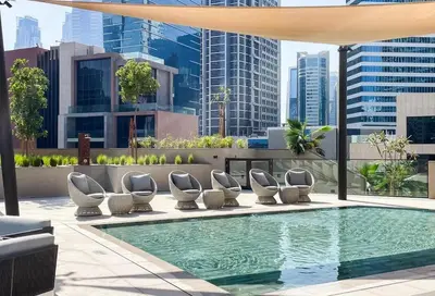 a swimming pool with lounge chairs and a building at Cozy Studio - Unit 1807 - Peninsula Five in Dubai