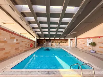 a large indoor swimming pool with blue water at Chic 1BR w Pool Sauna & Steam Room Access in Dubai