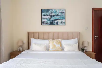 a bedroom with a large bed with white sheets and pillows at Chic 1BR w Pool Sauna & Steam Room Access in Dubai