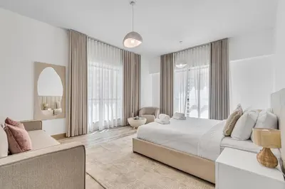 a white bedroom with a large bed and a chair at GYL Holiday Homes I Spacious 4 BDR Apt in JBR Beach, Dubai eye & Marina I Unbeatable location in Dubai