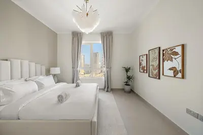 a white bedroom with a large white bed and a window at FIRST CLASS 2BR Burj and Fountain Cozy Luxe in Dubai