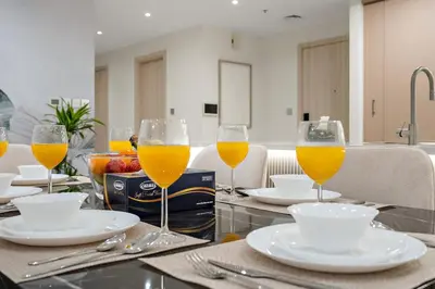 a table with three glasses of orange juice on it at FIRST CLASS 2BR Burj and Fountain Cozy Luxe in Dubai