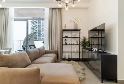 a living room with a couch and a table at Modern 1BR with Terrace, Rooftop Pool and PS5 in JVC in Dubai