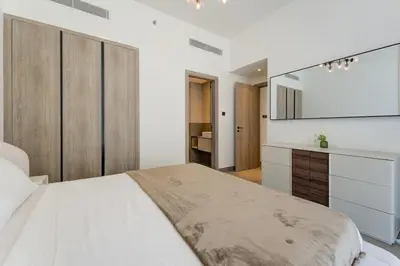 a white bedroom with a large bed and a counter at Modern 1BR with Terrace, Rooftop Pool and PS5 in JVC in Dubai