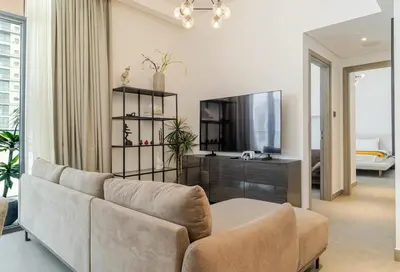 a living room with a couch and a television at Modern 1BR with Terrace, Rooftop Pool and PS5 in JVC in Dubai