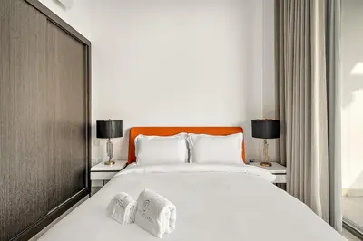 a bedroom with a large white bed with two lamps at FIRST CLASS 1BR Modern Serenity , Near Downtown in Dubai