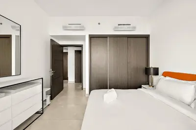 a white bedroom with a bed and a tv at FIRST CLASS 1BR Modern Serenity , Near Downtown in Dubai