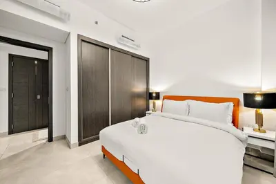 a bedroom with a large white bed and a brown cabinet at FIRST CLASS 1BR Modern Serenity , Near Downtown in Dubai
