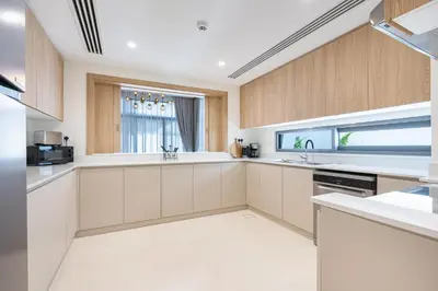 a large kitchen with white counters and wooden cabinets at Luxe 6BR Semi-Detached Villa Steps from the Lagoon in Dubai