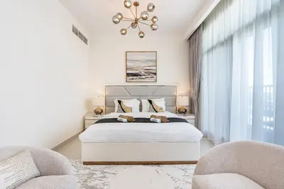 a bedroom with a large bed and two chairs at Luxe 6BR Semi-Detached Villa Steps from the Lagoon in Dubai