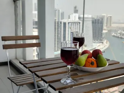 a table with a bowl of fruit and two glasses of wine at Burj View 1BHK near Down Town - Panoramic Balcony View -Pool and Gym in Dubai