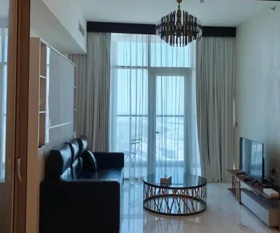 a living room with a black leather couch and a chandelier at Burj View 1BHK near Down Town - Panoramic Balcony View -Pool and Gym in Dubai
