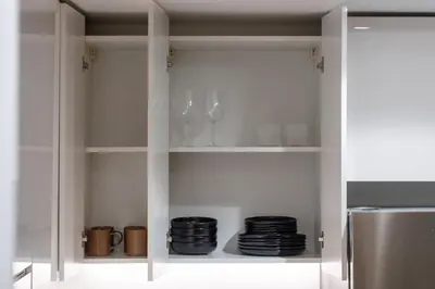 a white cabinet with wine glasses and plates at Meydan - Modern Family - 2BR Apartment - Azizi Riviera in Dubai