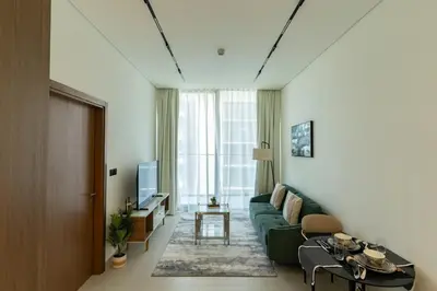 a living room with a green couch and a television at 1BR in Trillionaire Residences by Binghatti with canal view in Dubai