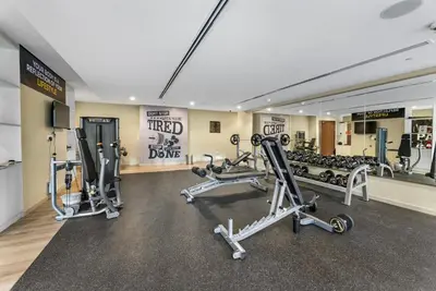a gym with several tread machines and a mirror at Waves - Modern City Escape 1BR Apt With Balcony in Dubai