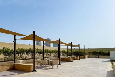 a patio with chairs and tables and umbrellas at High-Floor Studio Ghalia JVC with an Amazing View in Dubai