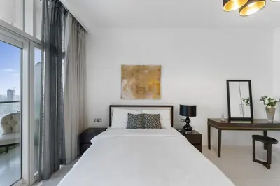 a white bedroom with a large bed and a desk at High-Floor Studio Ghalia JVC with an Amazing View in Dubai