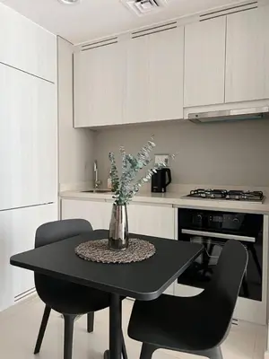 a kitchen with a table with chairs and a vase with flowers at Stylish 1BR in Zada Tower near Business Bay Metro in Dubai