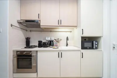 a kitchen with white cabinets and a stove and microwave at Luxury Upgraded Palm Studio with Marina and Yacht Views in Dubai