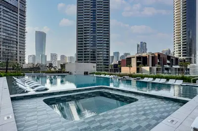 a large swimming pool with chairs and a city skyline at Modern Studio in Peninsula One with Canal Views in Dubai