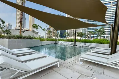 a swimming pool with lounge chairs and an umbrella at Modern Studio in Peninsula One with Canal Views in Dubai