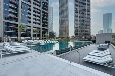 a pool in a city with chairs and buildings at Modern Studio in Peninsula One with Canal Views in Dubai