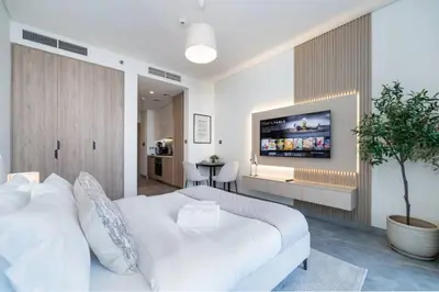 a bedroom with a white bed with a tv on the wall at Luxury Studio in Peninsula One, Bay Views in Dubai