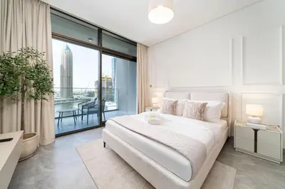 a white bedroom with a large bed and a large window at Luxury Studio in Peninsula One, Bay Views in Dubai