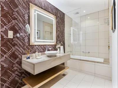 a bathroom with a sink and a mirror and a tub at Savis Homes - Stylish 1BR in Business Bay with Burj Khalifa View in Damac Paramount Tower in Dubai