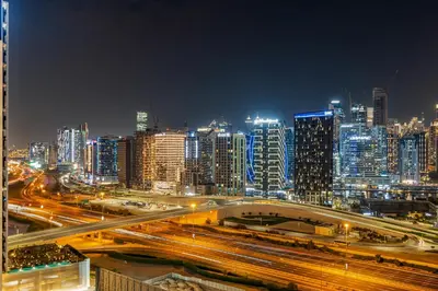 a city skyline at night with traffic on a freeway at Savis Homes - Stylish 1BR in Business Bay with Burj Khalifa View in Damac Paramount Tower in Dubai