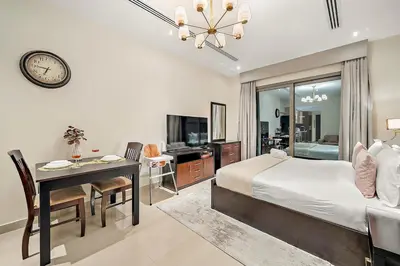 a bedroom with a bed and a desk and a clock at FIRST CLASS Studio Cozy with City Vibes in Dubai